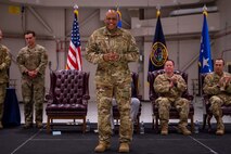 A man in military uniform stands centerstage, smiling at the audience in front of him.