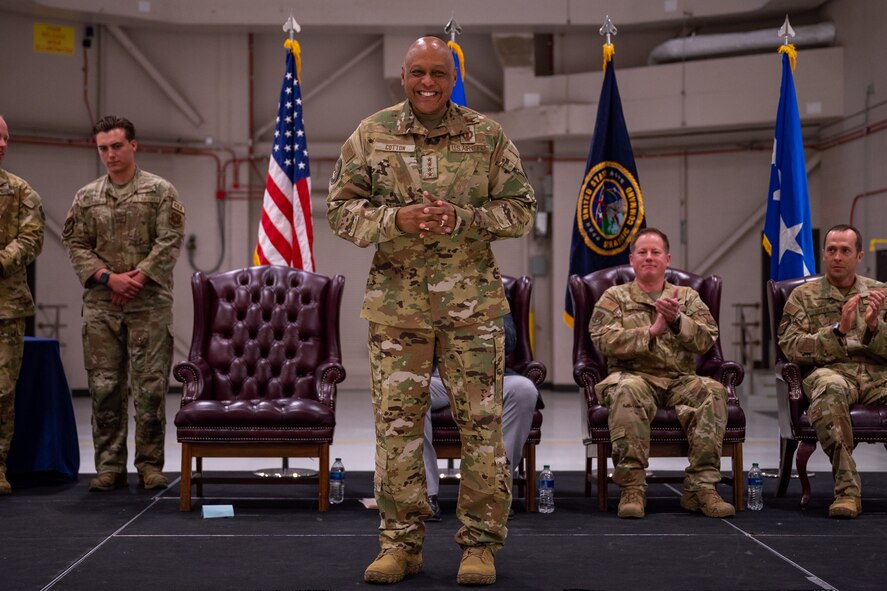 A man in military uniform stands centerstage, smiling at the audience in front of him.