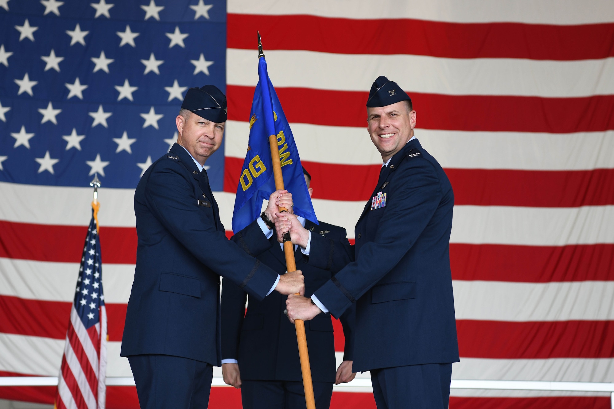 Two men in blue suits hold flag.