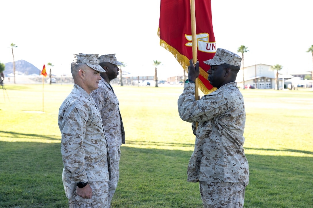 U.S. Marine Corps Sgt. Maj. Shonor Burton, Sergeant Major with Marine Corps Communications Electronics School (MCCES), (right), prepares to pass the battalion colors to Col. Joseph Broome