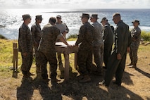 U.S. Marine Corps explosive ordnance disposal technicians stationed at Marine Corps Base Hawaii and a Navy explosive ordnance technician with Defense Personnel Accounting Agency participate in a brief during an explosive ordnance disposal excavation range, MCBH, June 21, 2023. The purpose of the excavation range was to practice employing additive self-manufactured shape charges to test the ease of use and capabilities. (U.S. Marine Corps photo by Cpl. Chandler Stacy)