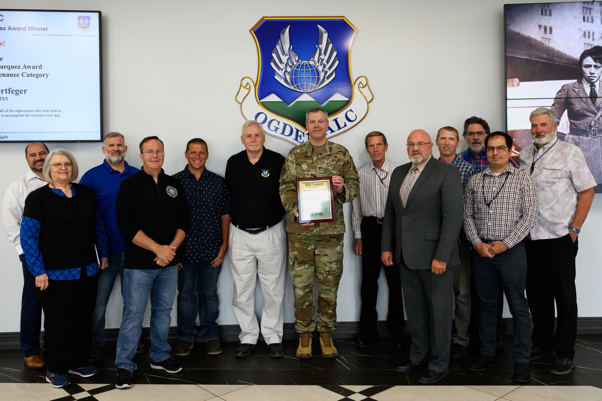 Officials pose for a group photo with the ISO 50001 recertification plaque.