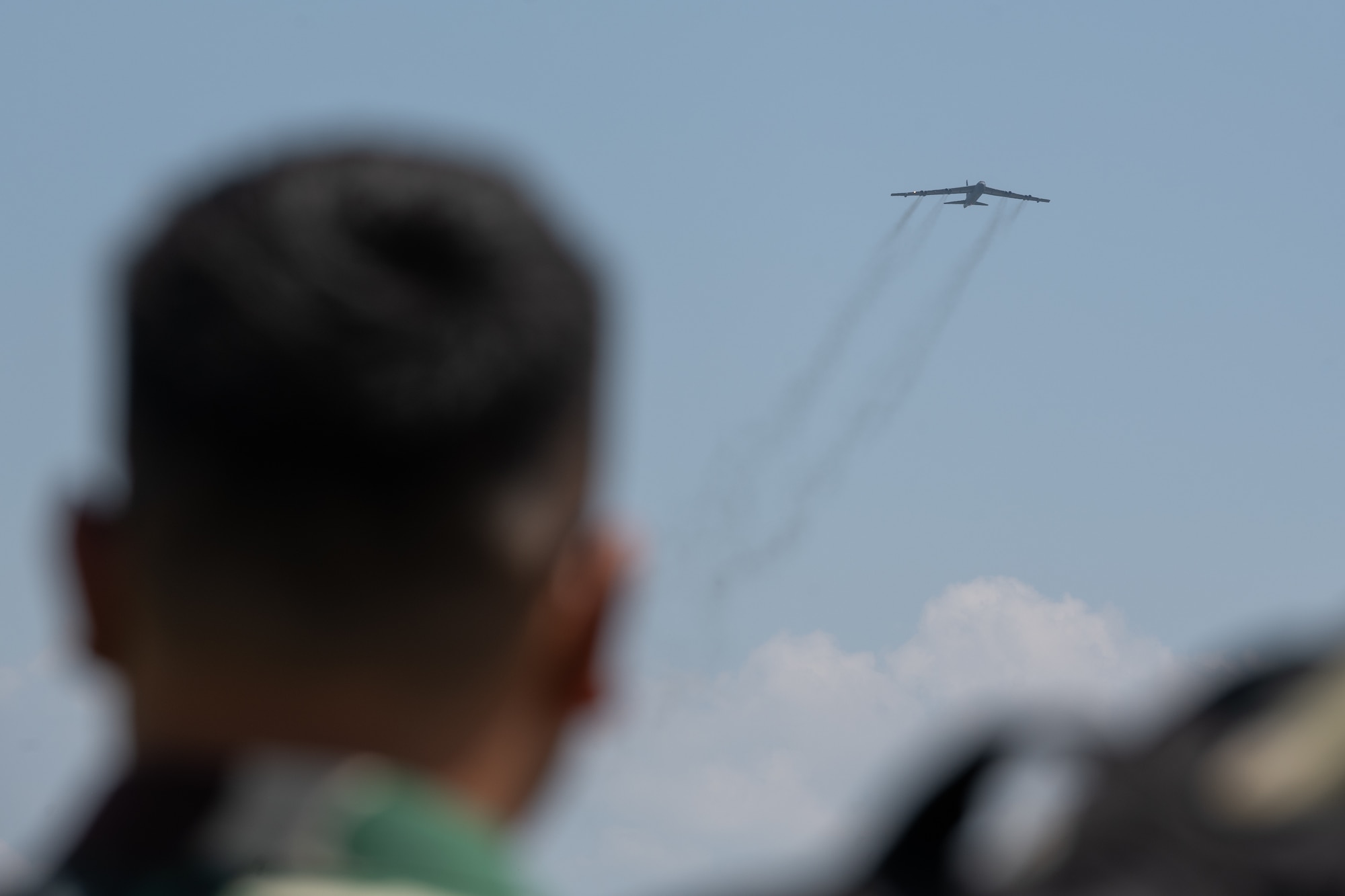 A member of the Tentara Nasional Indonesia Angkatan Udara, or Indonesian Air Force, watches as a U.S. Air Force B-52H Stratofortress assigned to the 23rd Bomb Squadron at Minot Air Force Base, North Dakota, approaches for landing at the Kualanamu International Airport in Medan, Indonesia, June 19, 2023. The arrival of the B-52 marked the first time a U.S. Air Force B-52 had landed on Indonesian soil. (U.S. Air Force photo by Tech. Sgt. Zade Vadnais)