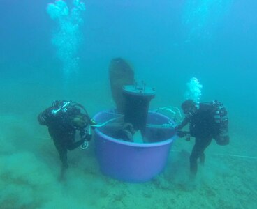 Two divers placing large device underwater