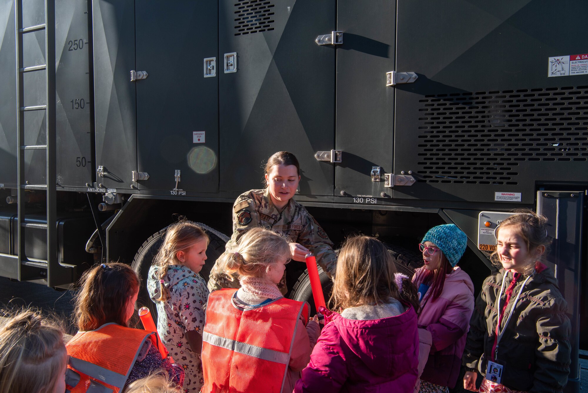 A service member talks about her job to kids.