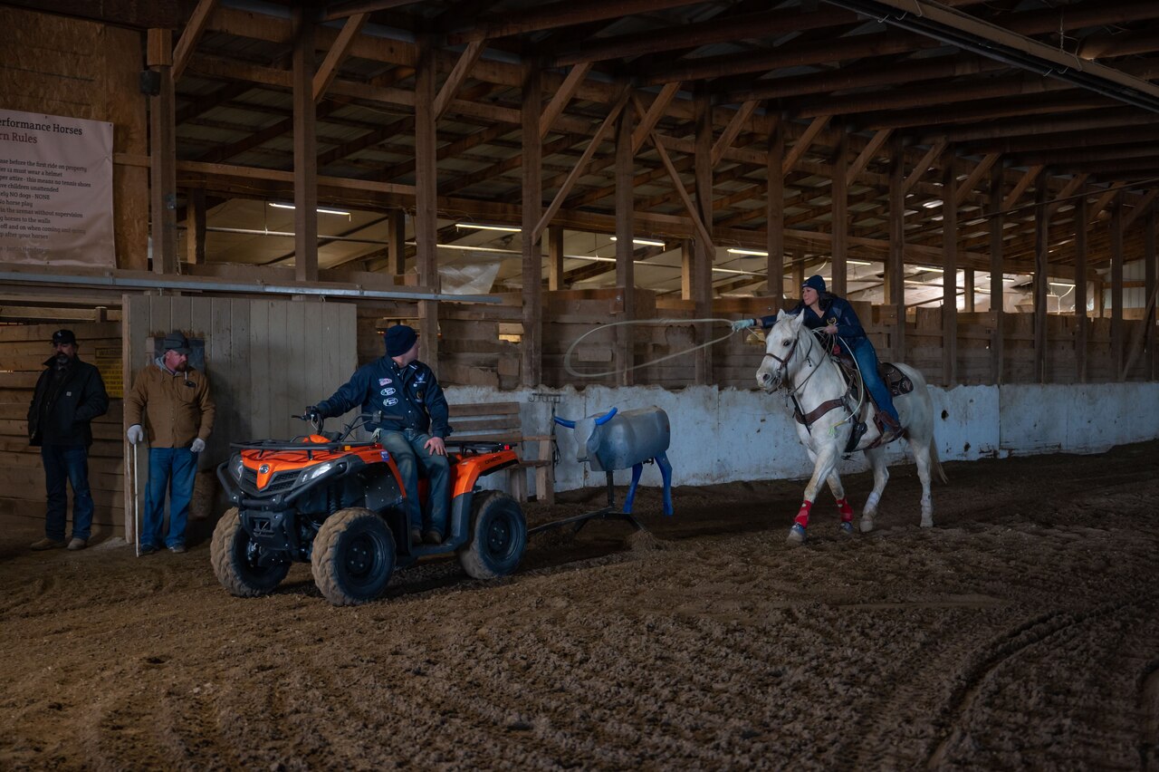 A person is shown riding a horse with a 4-wheel vehicle ahead of them.