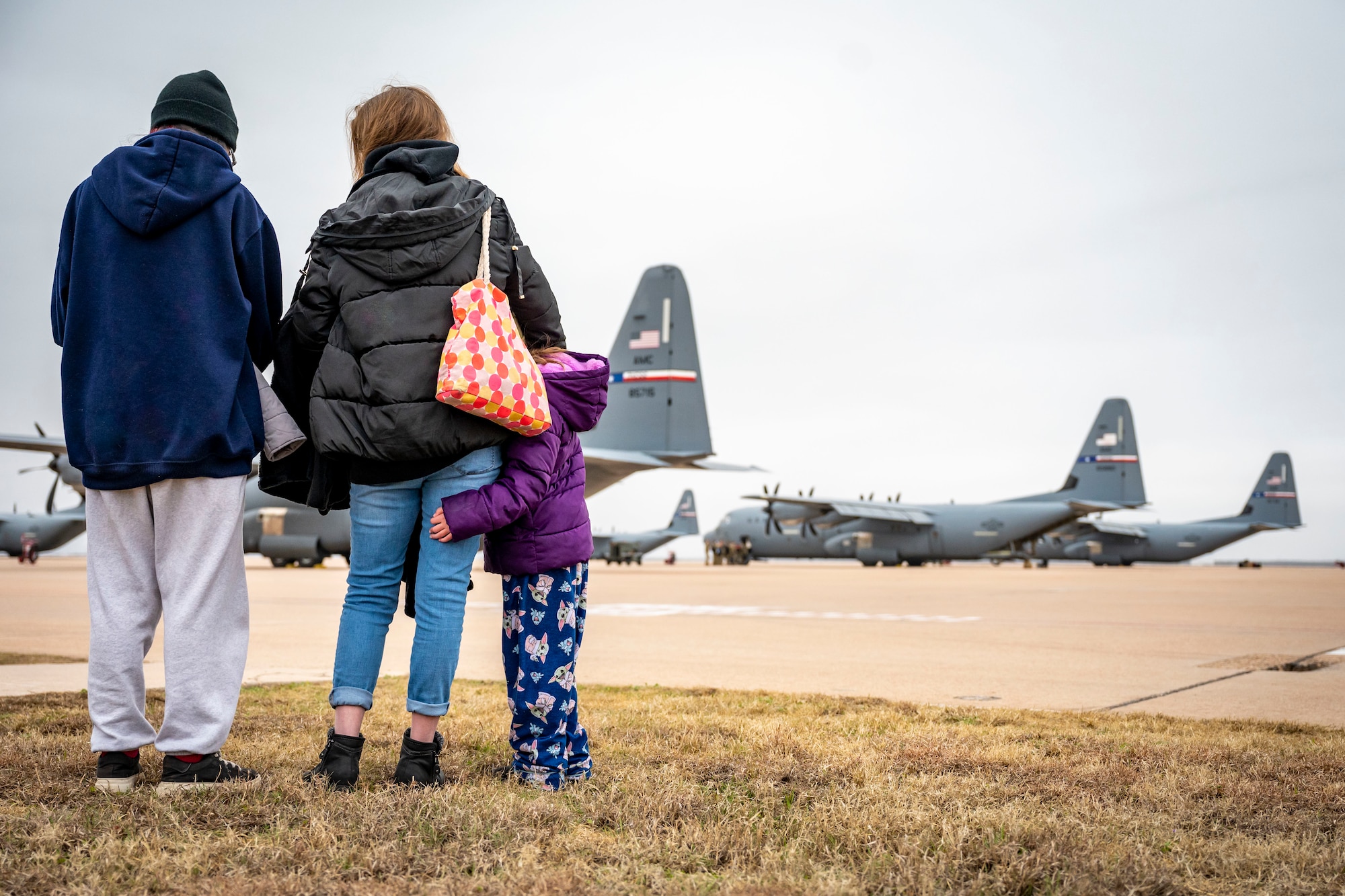 A family watches as U.S. Air Force Airmen assigned to the 317th Airlift Wing boards a C-130J Super Hercules before leaving for a deployment at Dyess Air Force Base, Texas, Feb. 25, 2023. Members from the 317th were deployed to the Middle East in support of the U.S. Central Command’s continued mission of enabling military operations and activities with allies and partners to increase regional security and stability in support of enduring U.S. interests. (U.S. Air Force photo by Senior Airman Leon Redfern)