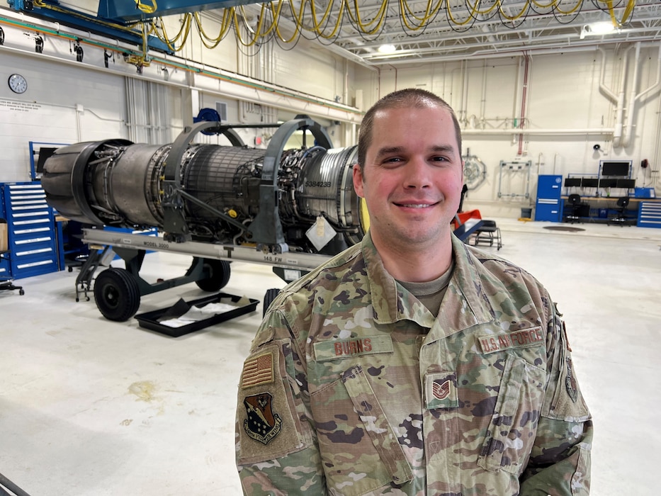 U.S. Air National Guard aerospace propulsion specialist, Tech. Sgt. Charles Burns, poses for a photo in front of an a General Electric F110-129 turbofan aircraft engine assigned to the 148th Fighter Wing, Minnesota Air National Guard, on February 16, 2023. Burns is one of seven airmen assigned to the 148th Fighter Wing who earned the highest possible ASVAB AFQT score of 99.