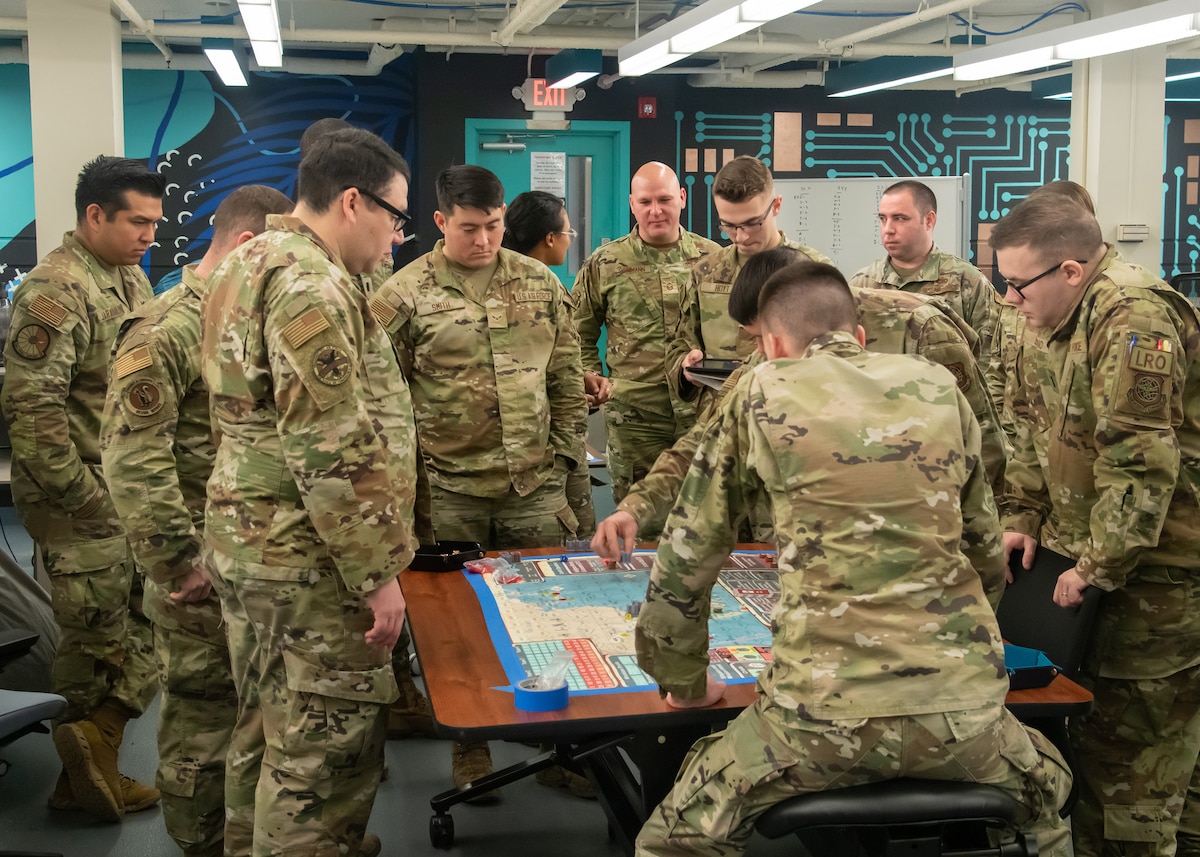 Team Dover Airmen gather to go over strategy and instruction for the Kingfish ACE wargame at Dover Air Force Base, Delaware, Jan. 19, 2023. The board game teaches agile combat employment to Airmen staged in future rapid global mobility contingency scenarios. (U.S. Air Force photo by Senior Airman Joshua LeRoi)