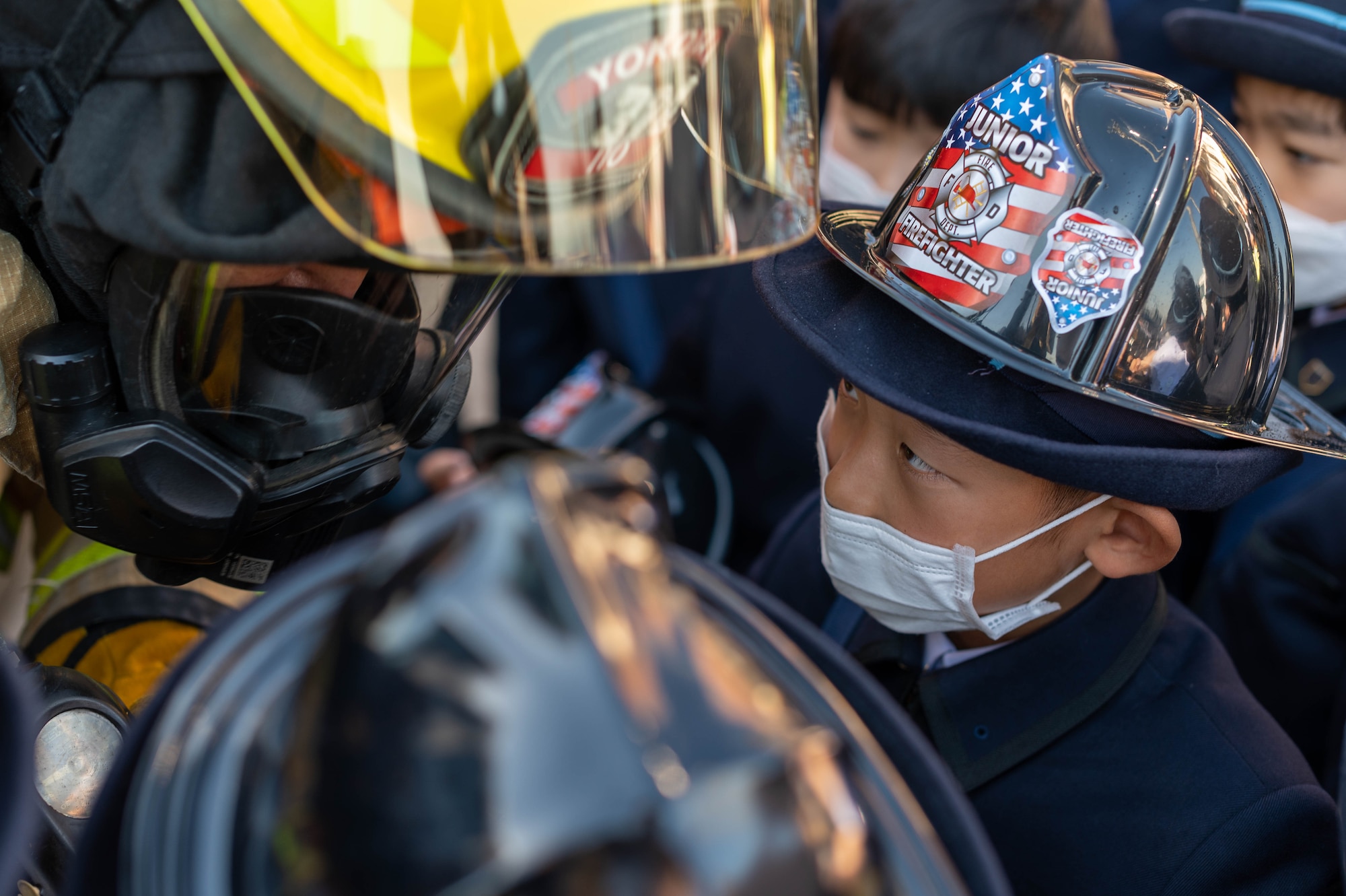 A Japanese child looks at a firefighter speaking to him.
