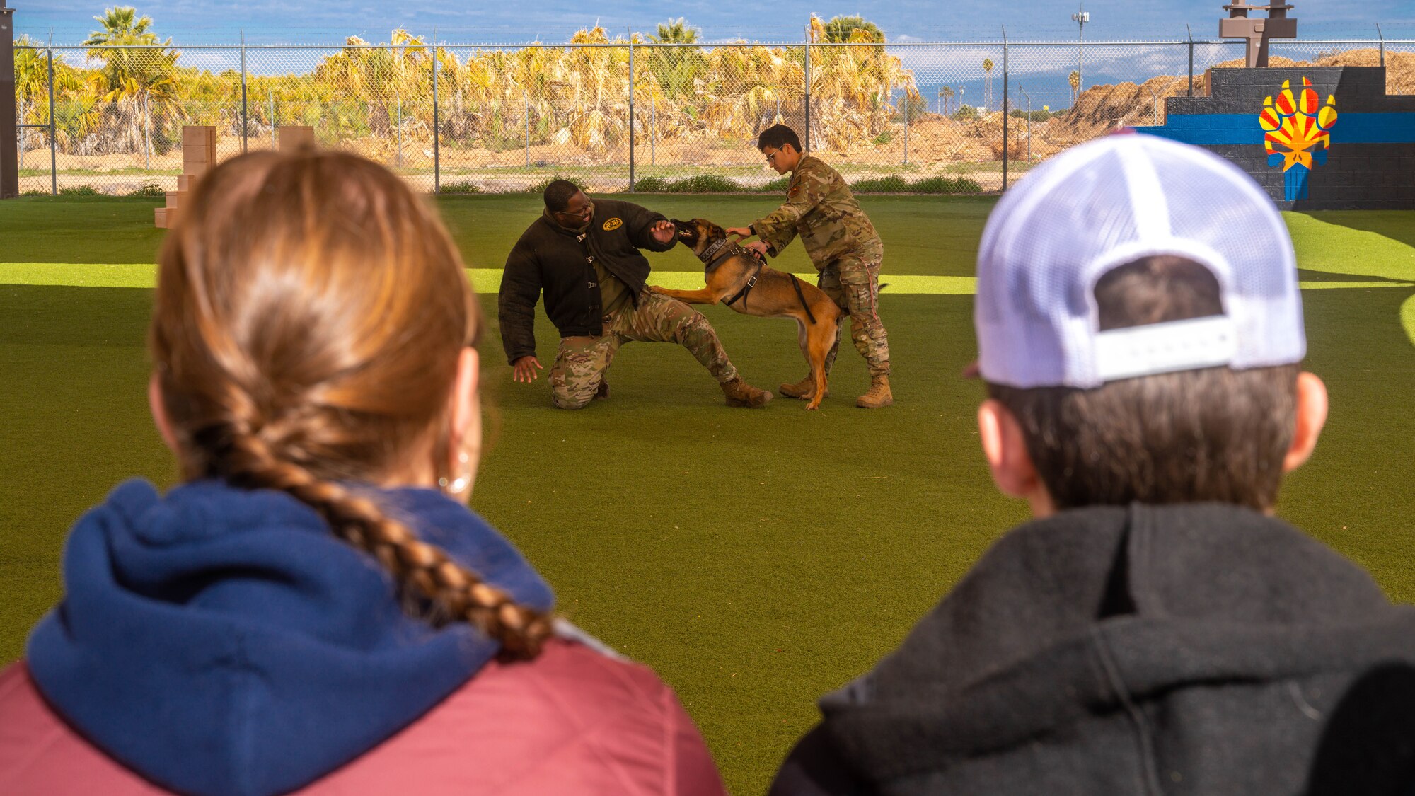 U.S. Air Force Staff Sgt. Daryan Hargrove (left), 56th Security Forces Squadron military working dog handler, and Staff Sgt. Elizabeth Pedroza (right), 56th Security Forces Squadron military working dog handler, demonstrate bite training to students from the Prescott High School Air Force JROTC unit, Feb. 21, 2023, at Luke Air Force Base, Arizona.