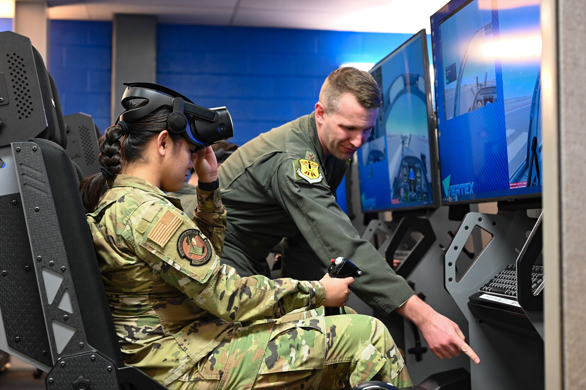 U.S. Air Force Airman 1st Class Natalie Bait (left), 47th Force Support Squadron career development technician, wears a virtual reality headset as Maj. Jeffrey Nixon, 47th Operations Group executive officer, at Laughlin Air Force Base, Texas, explains various controls in a T-6 Texan II simulator on Feb. 22, 2023.