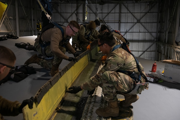 airmen working on an aircraft's wing