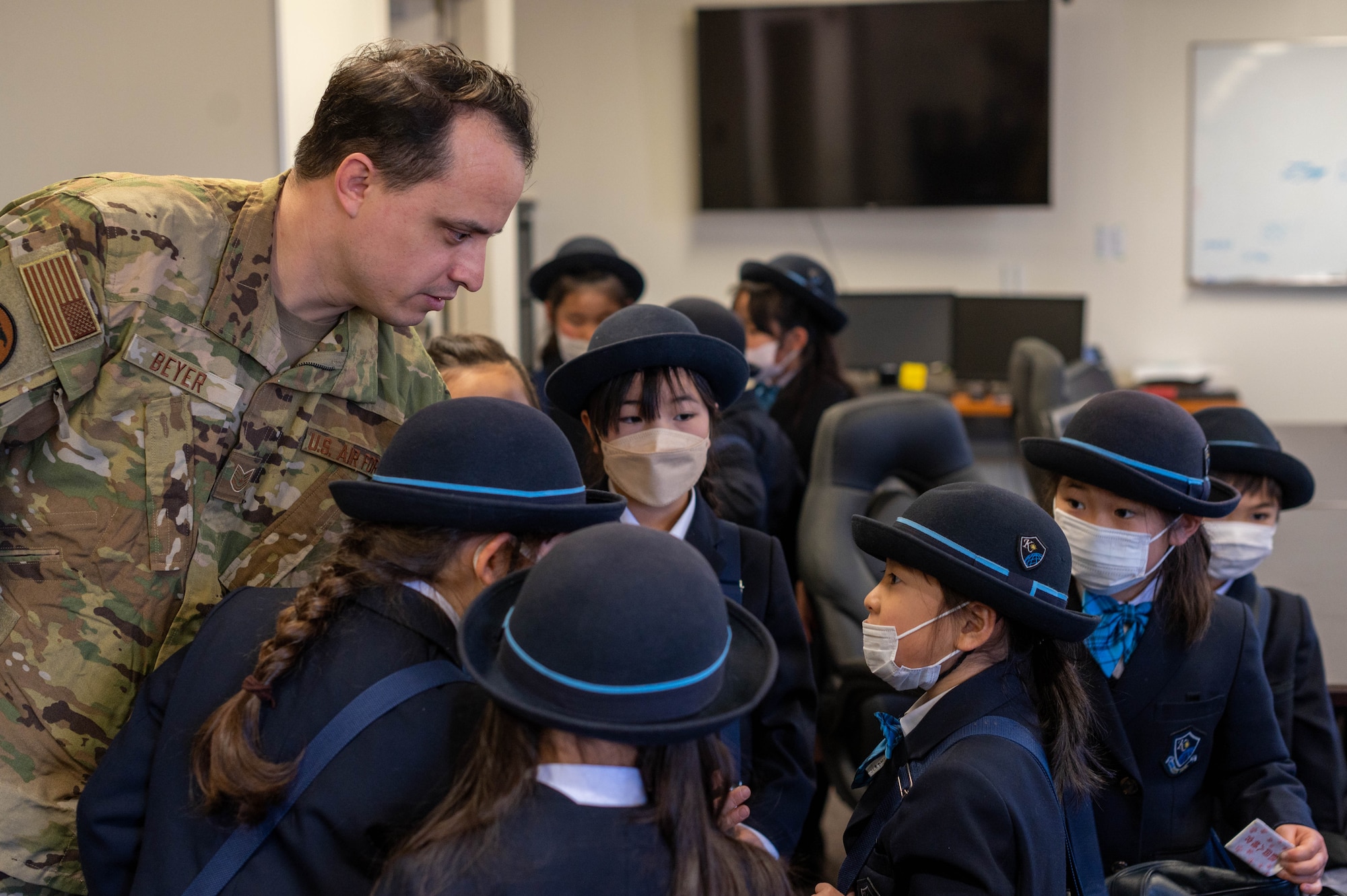 A white man leans down to listen to a Japanese girl asking a question.