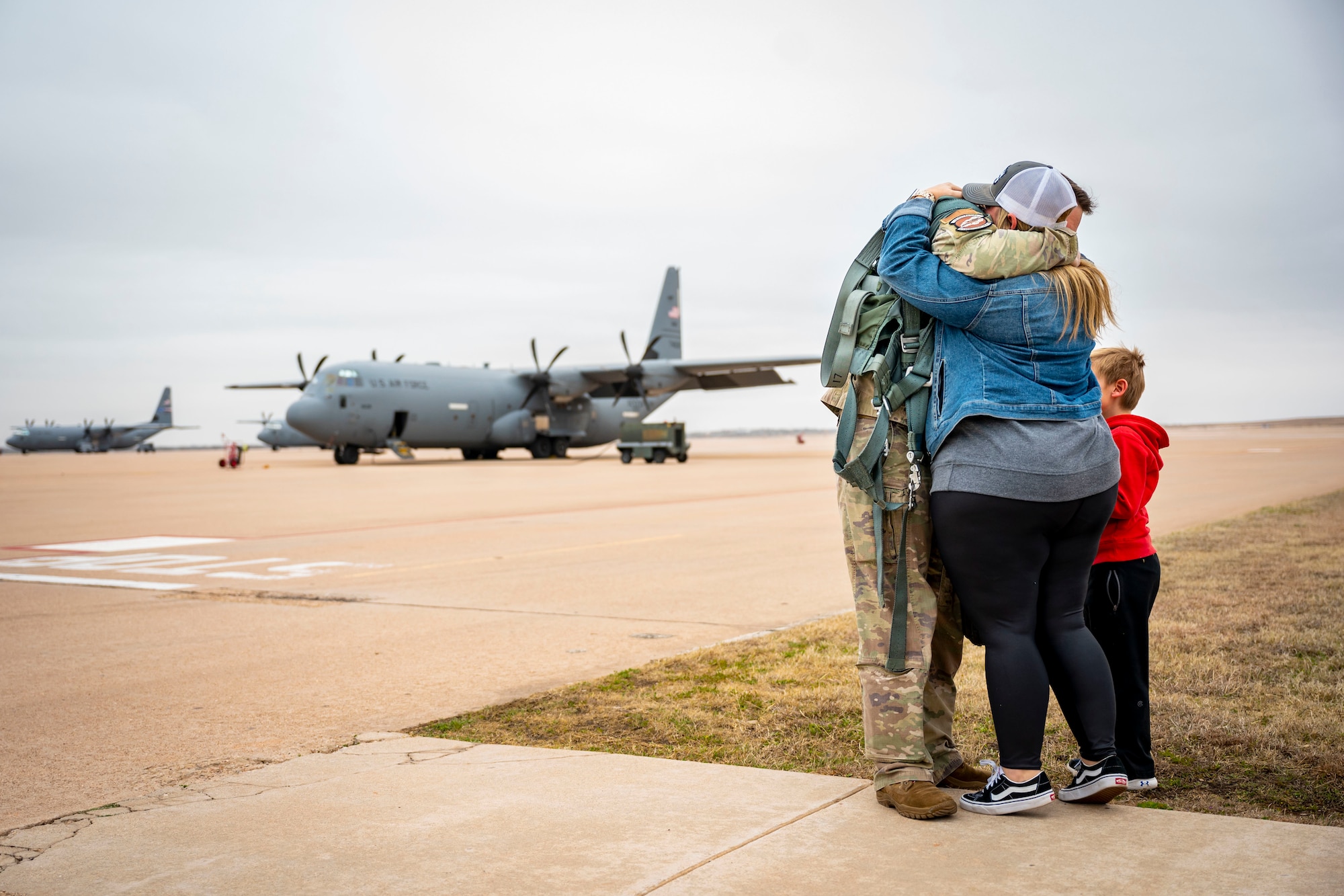 A U.S. Air Force Airman assigned to the 317th Airlift Wing hugs his family goodbye before leaving for a deployment at Dyess Air Force Base, Texas, Feb. 25, 2023. Members from the 317th were deployed to the Middle East in support of the U.S. Central Command’s continued mission of enabling military operations and activities with allies and partners to increase regional security and stability in support of enduring U.S. interests. (U.S. Air Force photo by Senior Airman Leon Redfern)