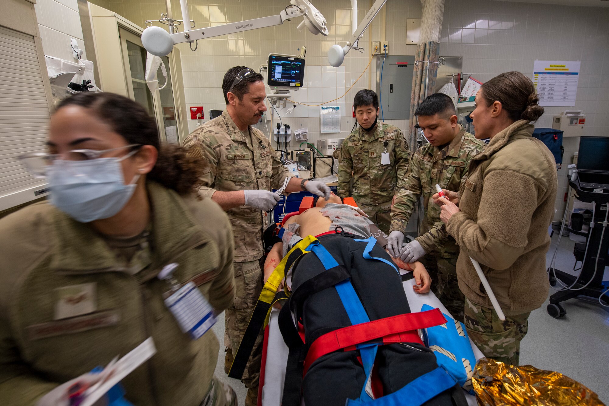 U.S. Air Force Airmen from the 51st Medical Group (MDG) cut the shirt off of Kwang Pil Pak, 51st MDG warrior medicine clinic administrator and simulated trauma patient, at the urgent care on Osan Air Base, Republic of Korea, Feb. 28, 2023.  This training event enabled the Airmen to apply life-saving training to a variety of real-world situations. (U.S. Air Force photo by Airman 1st Class Aaron Edwards)