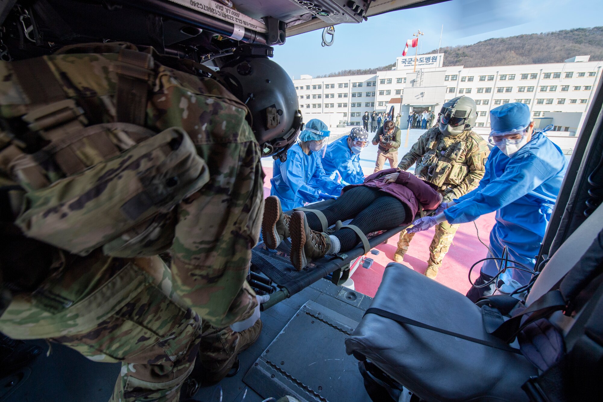 U.S. Army Staff Sgt. Michael Mongia, 3-2 General Support Aviation Battalion flight paramedic, left, Spc. Noah Quevedo 32nd GSAB crew chief, and Republic of Korea Armed Forces Trauma Center (AFTC) personnel unload U.S. Air Force Master Sgt. Szymanski, simulated trauma patient from a HH-60M Black Hawk, onto the helipad at the ROK AFTC, Republic of Korea, Feb. 28, 2023. The 3-2 GSAB personnel worked directly with the 51st Medical Group and ROK AFTC to transport the patient from Osan Air Base to the ROK AFTC for further treatment.  (U.S. Air Force photo by Airman 1st Class Aaron Edwards)