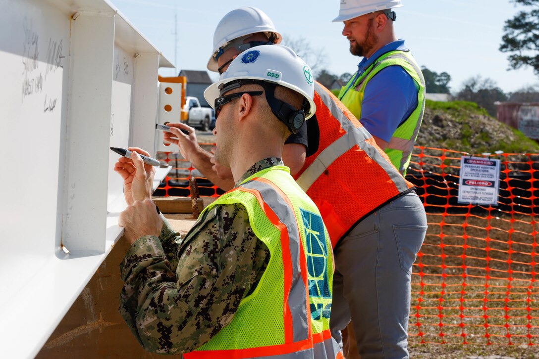 Lt. Cmdr. David Dreyer, Resident Officer In-Charge of Construction Cherry Point, signs the final steel structural beam during the topping out ceremony for the future auditorium on Marine Corps Air Station (MCAS) Cherry Point, North Carolina, Feb. 22, 2023. The auditorium is part of the recovery construction to rebuild and modernize structures damaged by Hurricane Florence. The topping out ceremony is a celebration of the facility structure being completed and the next stage of construction beginning. (U.S. Marine Corps photo by Lance Cpl. Lauralle Walker