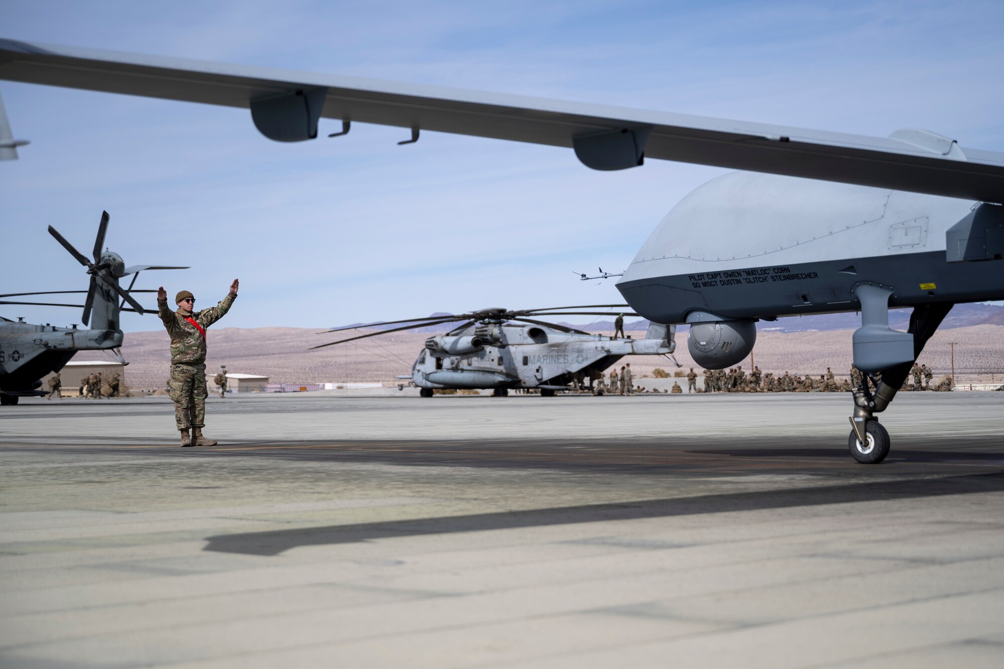 U.S. Air Force Senior Airman Kyle Thompson, 29th Aircraft Maintenance Unit systems apprentice, marshals an MQ-9 Reaper at Marine Corps Air Ground Combat Command Center, Twentynine Palms, California, Feb. 16, 2023. Agile Combat Employment Reaper involved the use of Holloman MQ-9s and U.S. Marine Corps CH-53E Super Stallions. (U.S. Air Force photo by Staff Sgt. Kristin West)