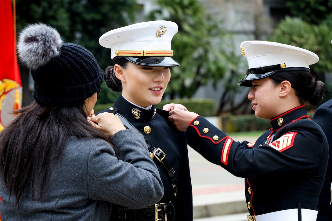 A Marine is pinned by two people during a commissioning ceremony.