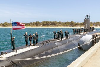 Sailors aboard USS Asheville (SSN 758) salute the national ensign after arriving at Stirling Naval Base in Australia.