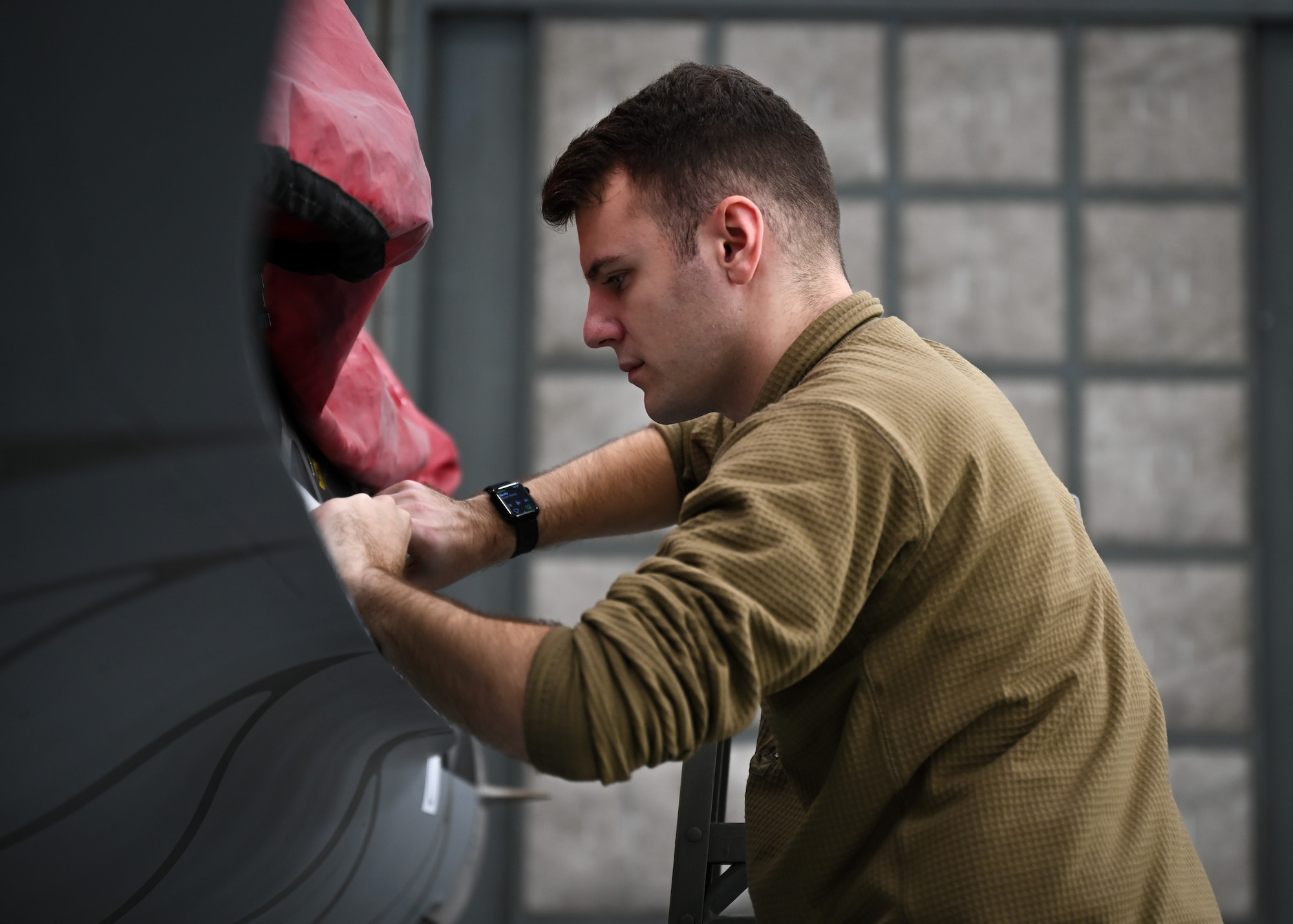 U.S. Air Force Airman secures stencil to an F-16C Fighting Falcon