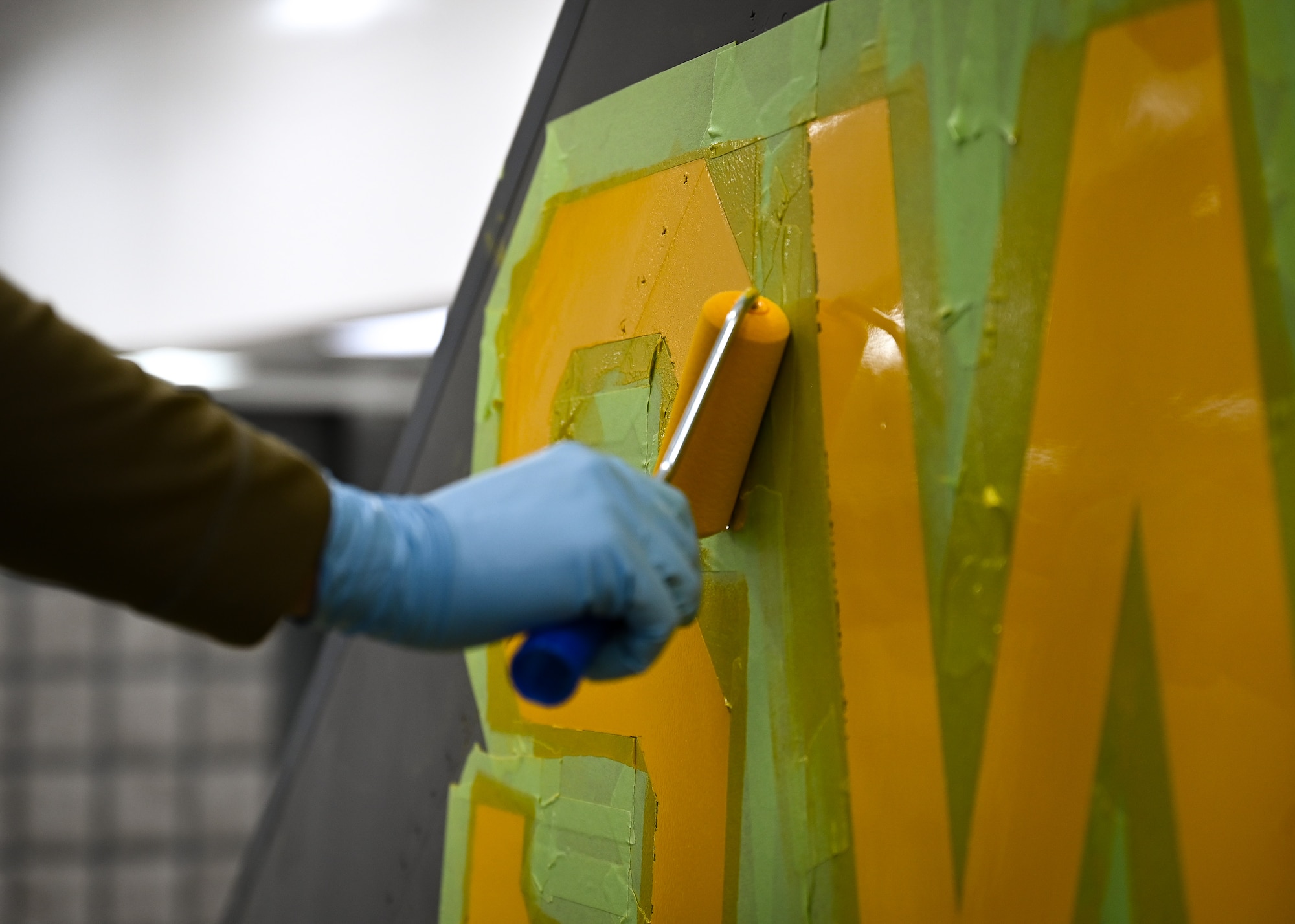 U.S. Air Force Airman applies layer of paint to F-16C Fighting Falcon