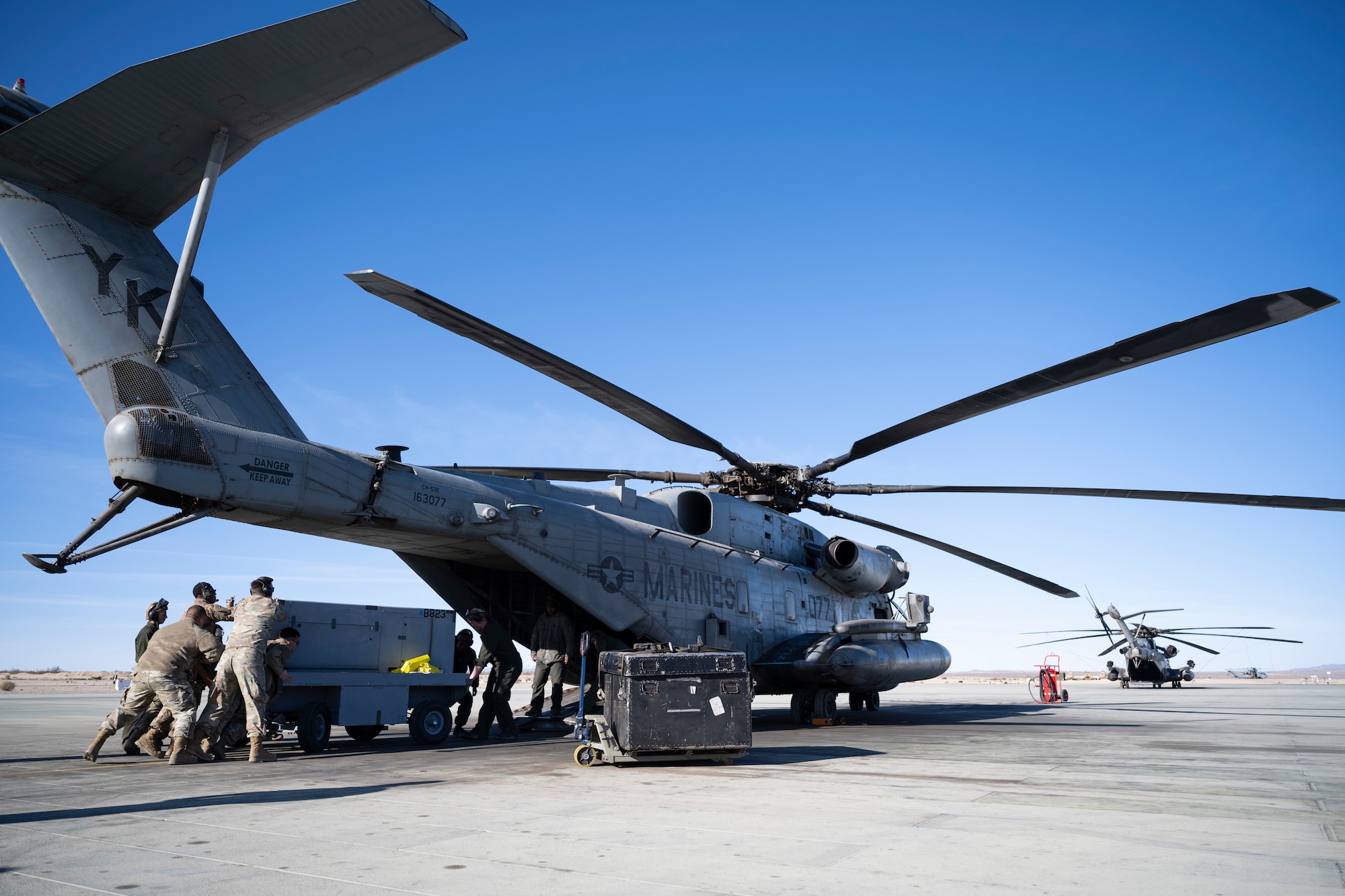 Airmen from the 9th and 29th Aircraft Maintenance Units load a hybrid flightline generator into an CH-53E Super Stallion at Marine Corps Air Ground Combat Command Center, Twentynine Palms, California, Feb. 16, 2023. Agile Combat Employment Reaper 23.6 saw Holloman Air Force Base Airmen being trained by Cannon AFB, N.M., Airmen on how to use a Portable Aircraft Control System. (U.S. Air Force photo by Staff Sgt. Kristin West)