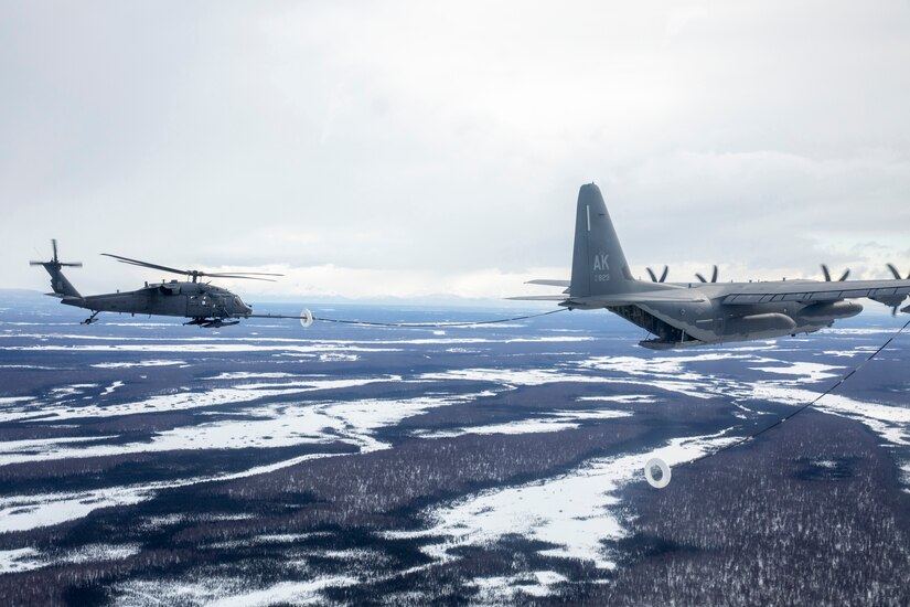 An aircraft refuels a helicopter in midair.