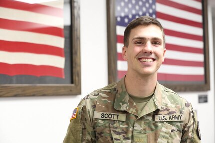 Officer Candidate Garrett Scott, with College of the Ozarks Bobcat Guard Officer Leadership Development (GOLD) Program, stands in front of a flag display at the College of the Ozarks William S. Knight (WSK) Center for Patriotic Education, Point Lookout, Mo., Nov. 18, 2022. Scott is in his senior year of school and is preparing for his new role as an executive officer at the 1107th Aviation Group (Photo by U.S. Army National Guard Spc. Rose Di Trolio).