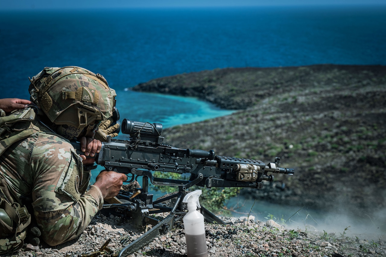 A soldier shoots a machine gun.