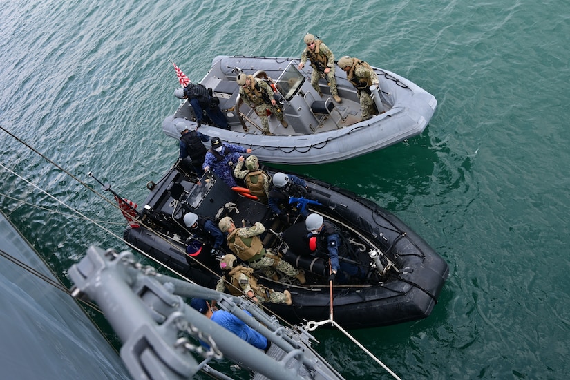 A camera looks down on service members in two small boats.