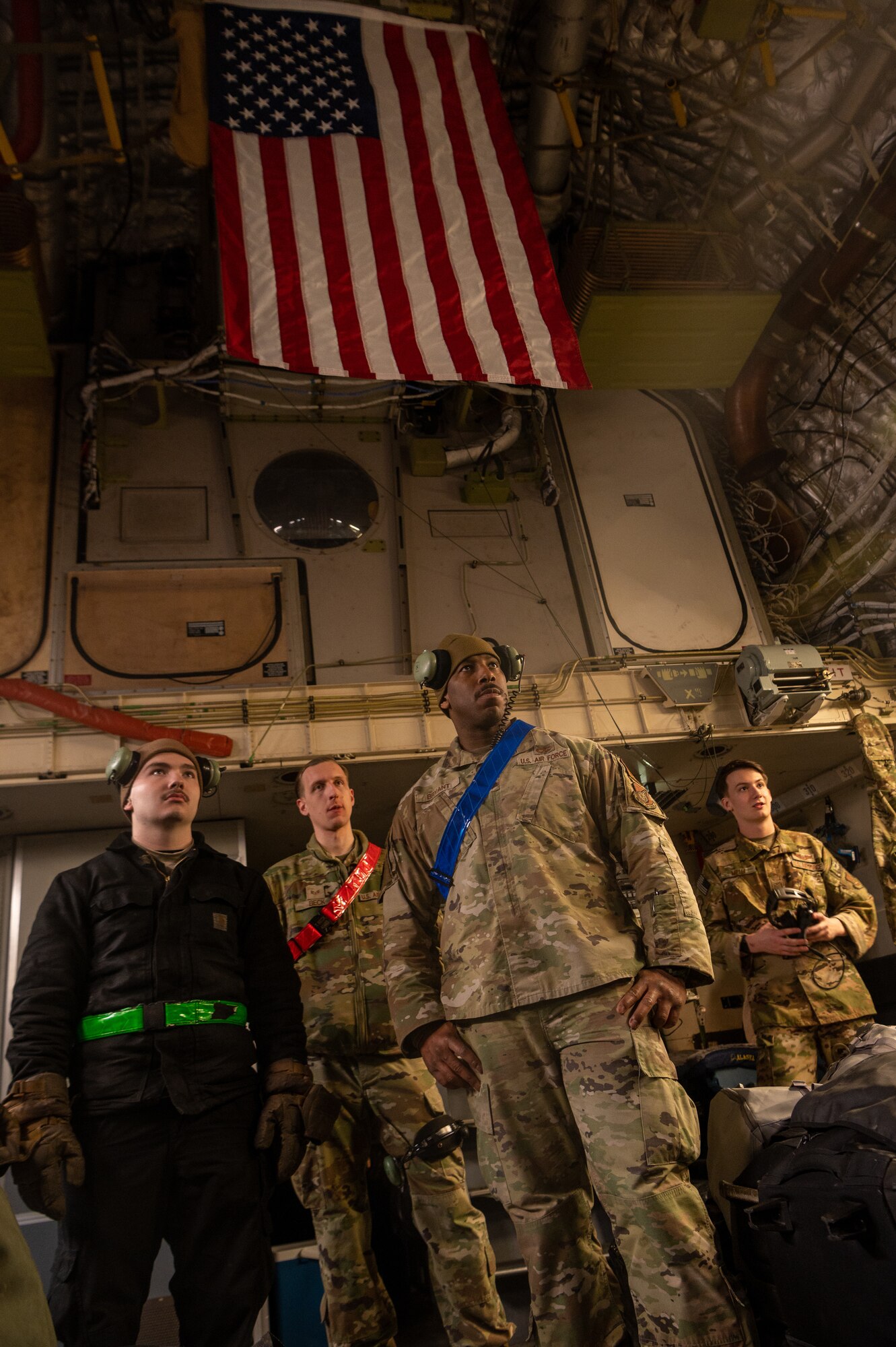 A photo of Airmen standing beneath an American flag inside a C-17
