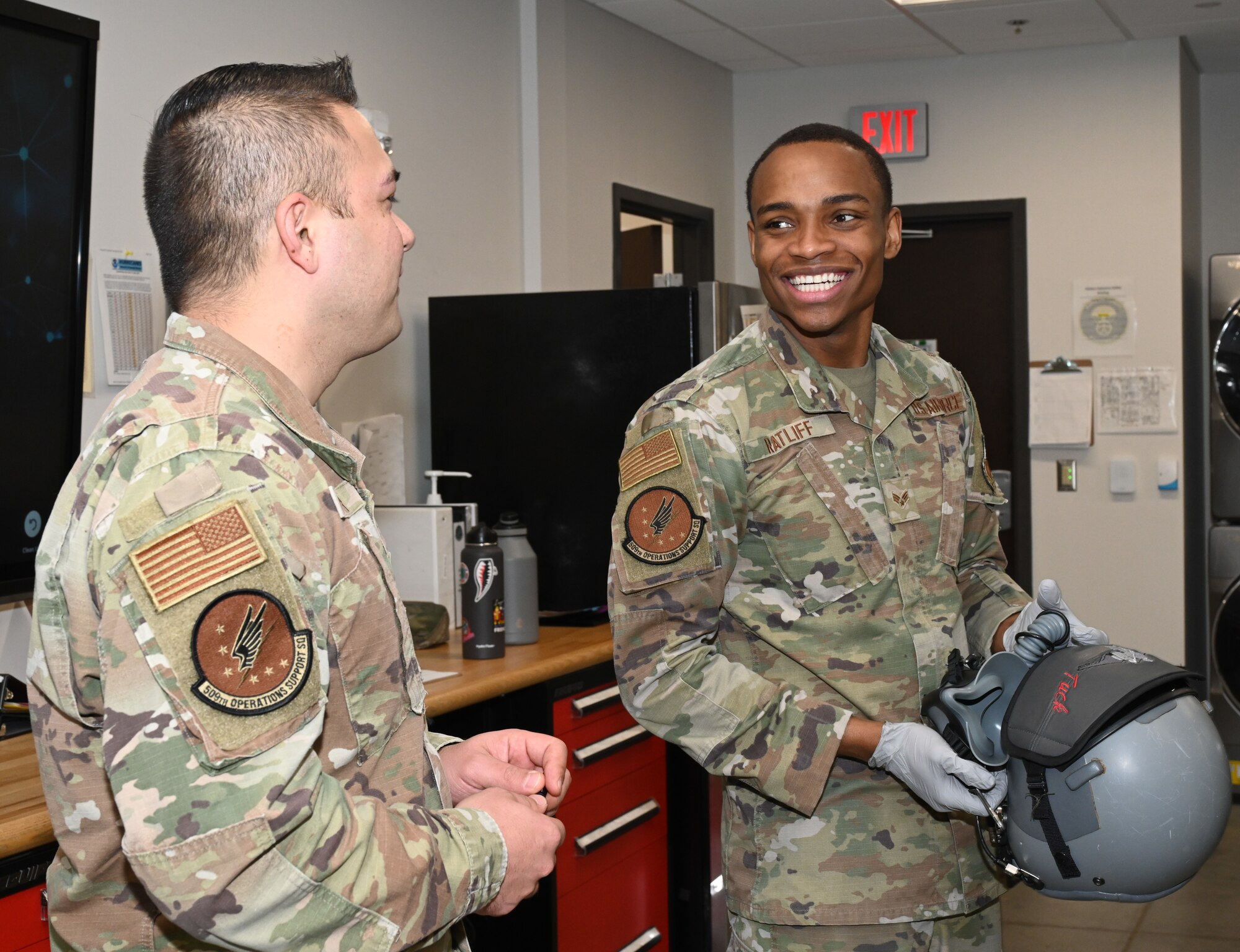 Technical Sgt. Steven Potter, Aircrew Flight Equipment section chief, and Senior Airman Anthony Ratliff, Aircrew Flight Equipment journeyman, both assigned to the 509th Operations Support Squadron, speak about conducting a routine inspection on an aircrew member’s HGU-55p helmet and MBU-20p mask at Whiteman Air Force Base, Missouri, Feb. 13, 2023. Routine inspections on these items are performed every 30 days to ensure flight equipment is in good working conditions. (U.S. Air Force photo by Airman 1st Class Hailey Farrell)