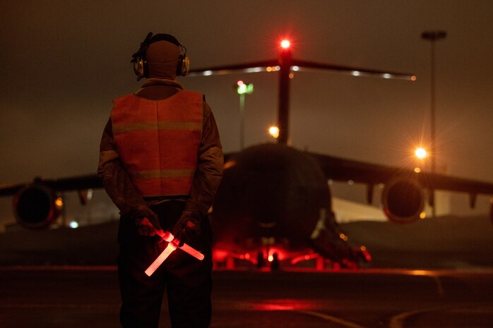 A photo of an Airman preparing to marshal a C-17