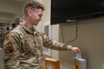 Airman puts slip of paper into grey box.