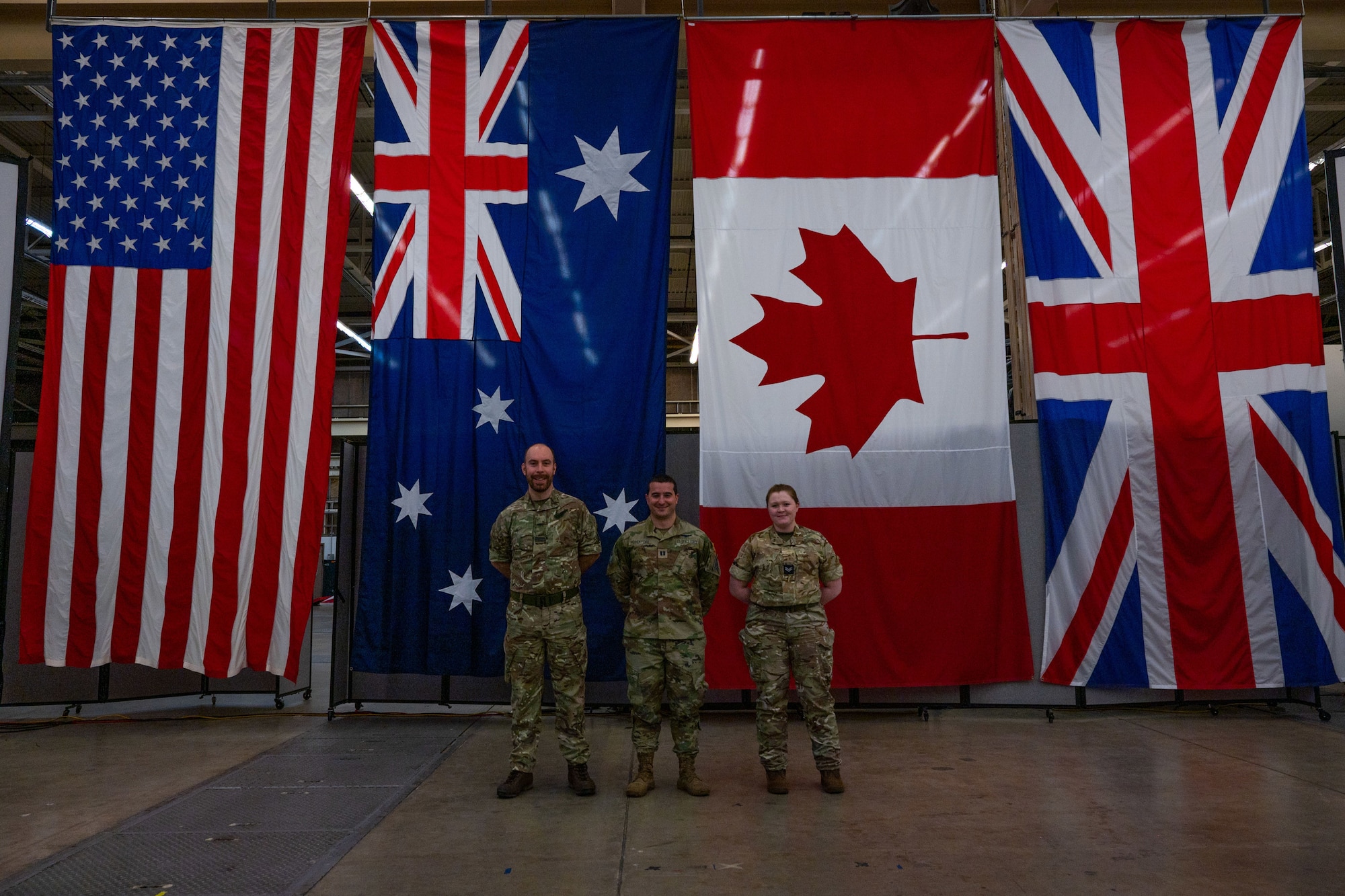 (From left to right) Royal Air Force (RAF) Flying Officer Hallchurch, U.K. Space Operations Centre (UKSpOC) space duty officer, U.S. Space Force Capt. Dustin Pessatore, 18th Space Defense Squadron (18 SDS) sharing coordinator, and RAF Corporal Coulson, UKSpOC space analyst, stand in front of flags in 18 SDS’s High Bay at Vandenberg Space Force Base, Calif., Feb. 13, 2023. According to U.K.’s Defence Space Strategy, the nation is focusing heavily on strengthening relations with Five Eyes intelligence partnerships and adopting an ‘international by design’ approach. (U.S. Space Force photo by Tech. Sgt. Luke Kitterman)