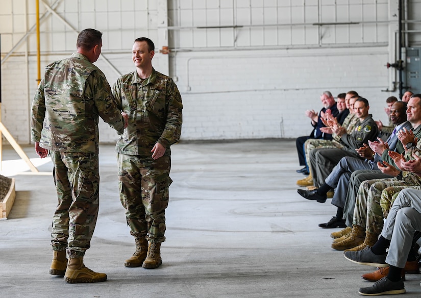 U.S. Air Force Col. Gregory Beaulieu, Joint Base Langley-Eustis installation commander, coins Tech. Sgt. Patrick Squires, 27th Fighter Generation Squadron Low Observable section chief, at JBLE, Virginia, Feb. 22, 2023.