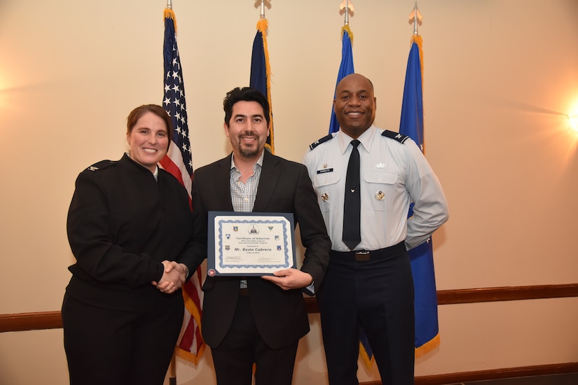 A woman and two men pose with a certificate.