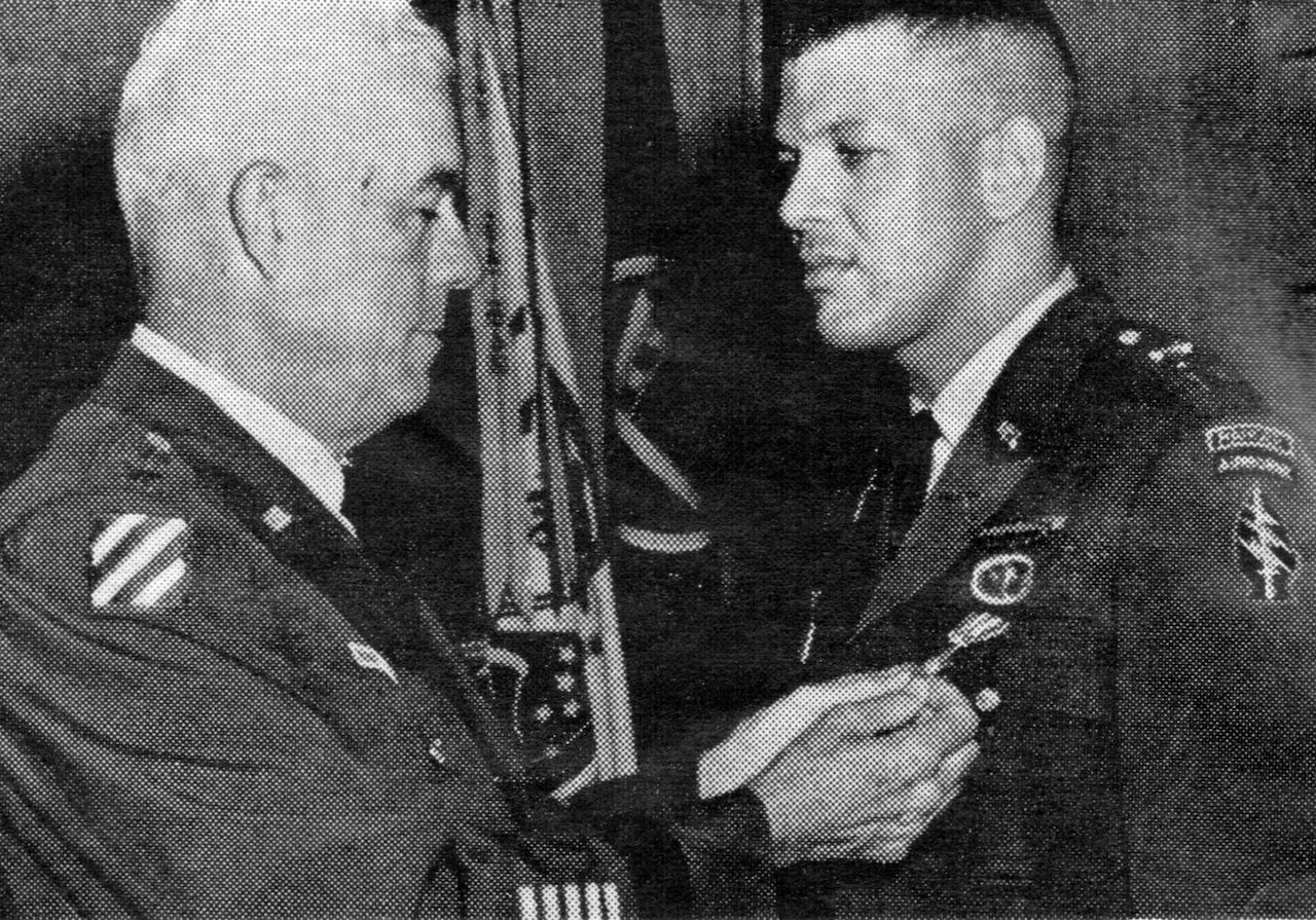 A man pins a medal on the uniform of a soldier.