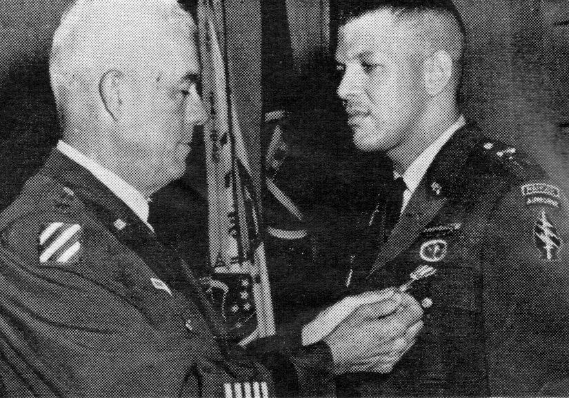 A man pins a medal on the uniform of a soldier.