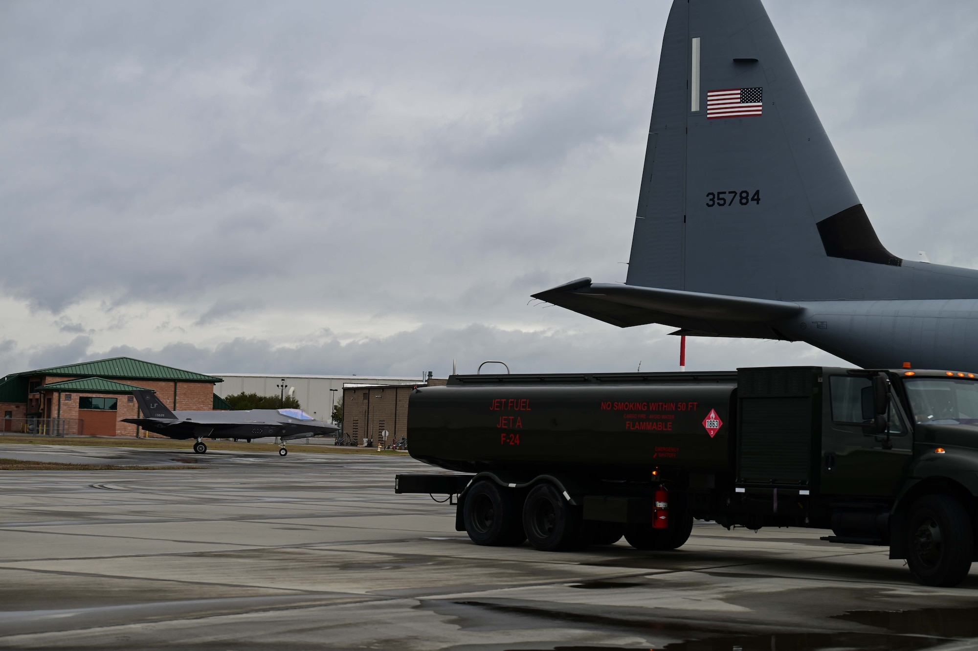 A C-130J Cargo plane fuels an F-35 Fighter jet on the flightline
