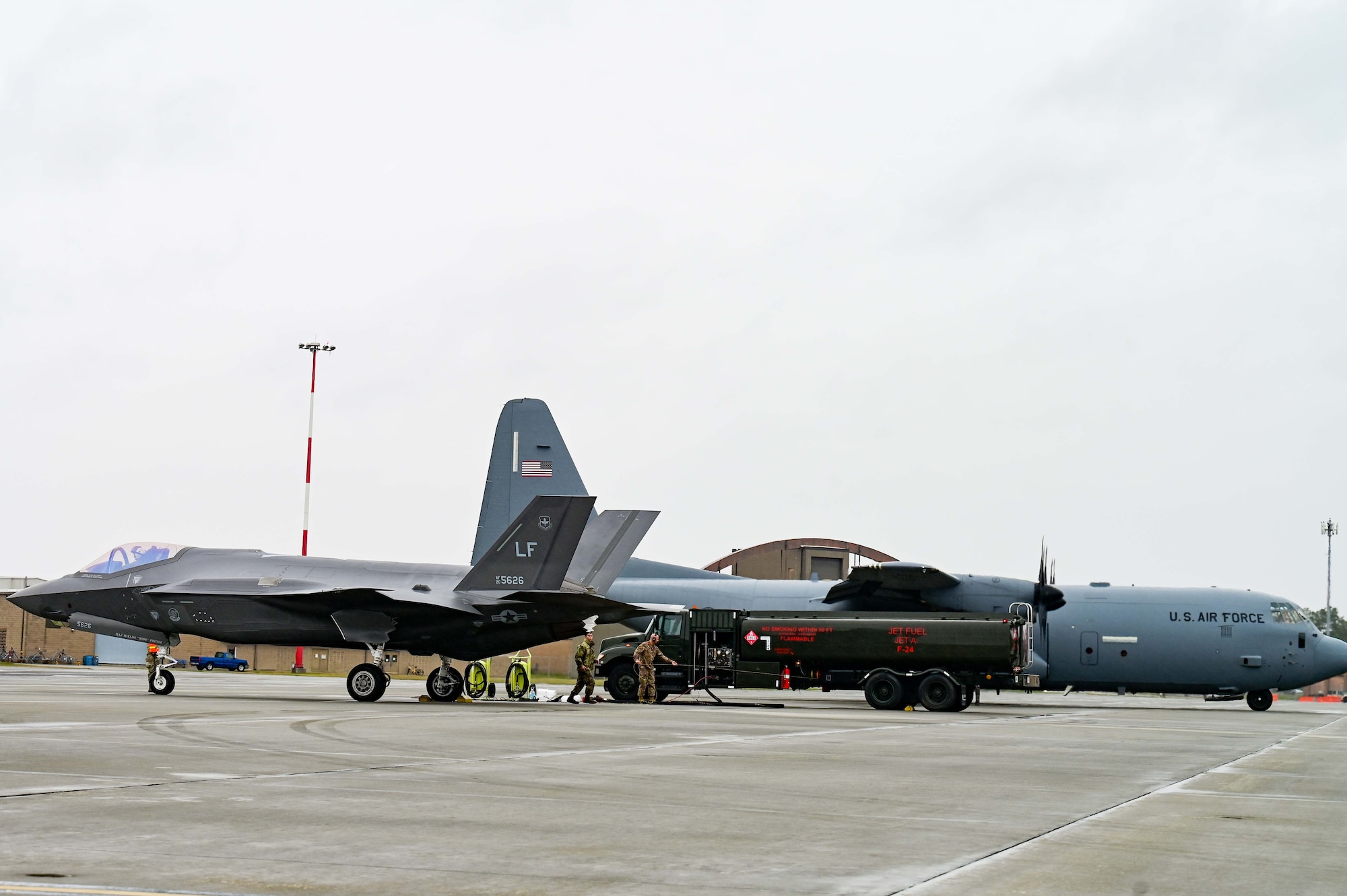 A C-130J Cargo plane fuels an F-35 Fighter jet on the flightline
