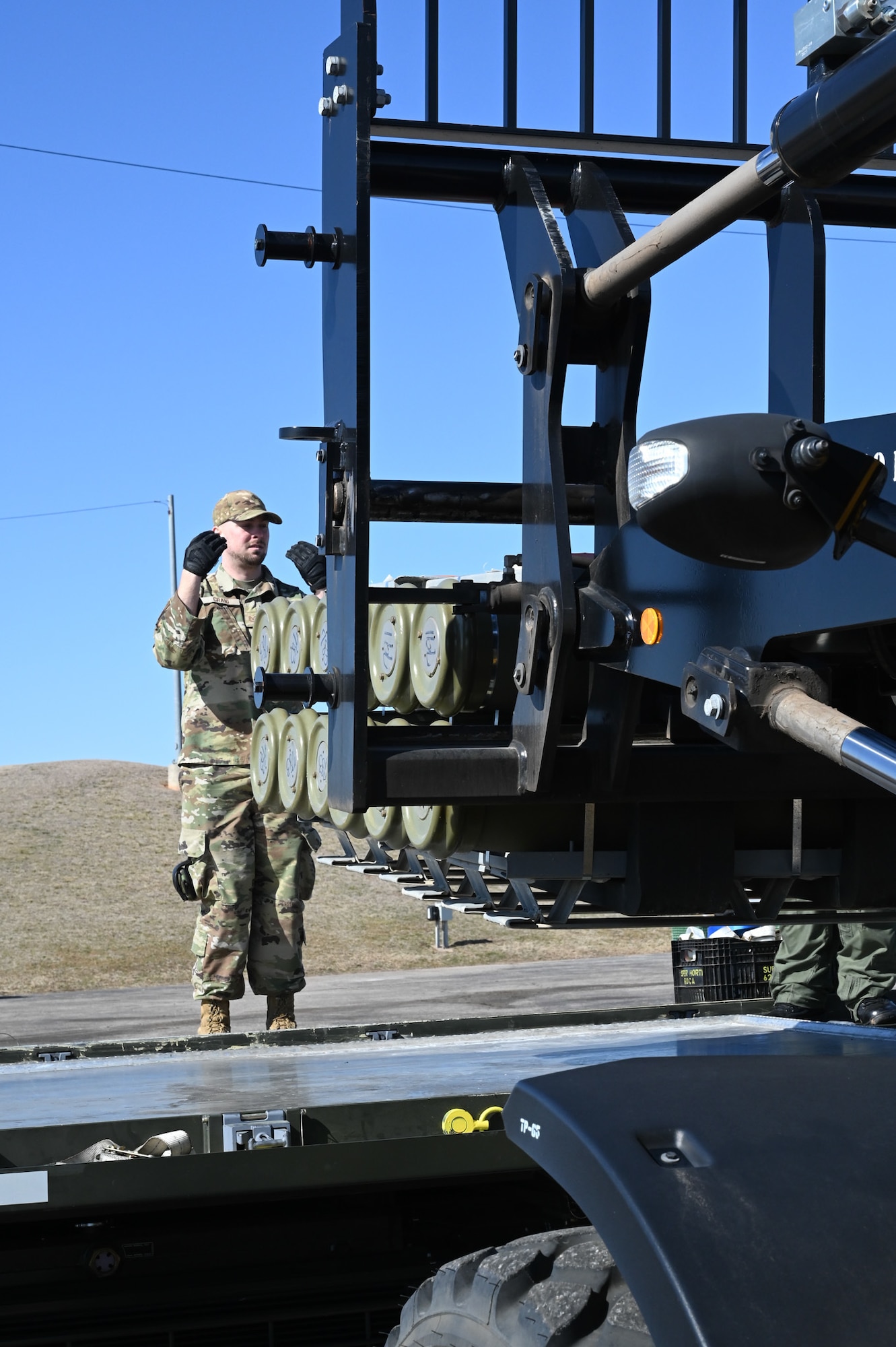 airman guiding fork lift carrying munitions