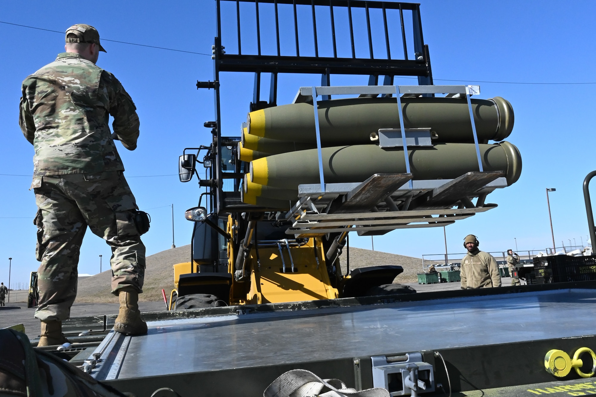 airman guiding fork lift with munitions toward truck