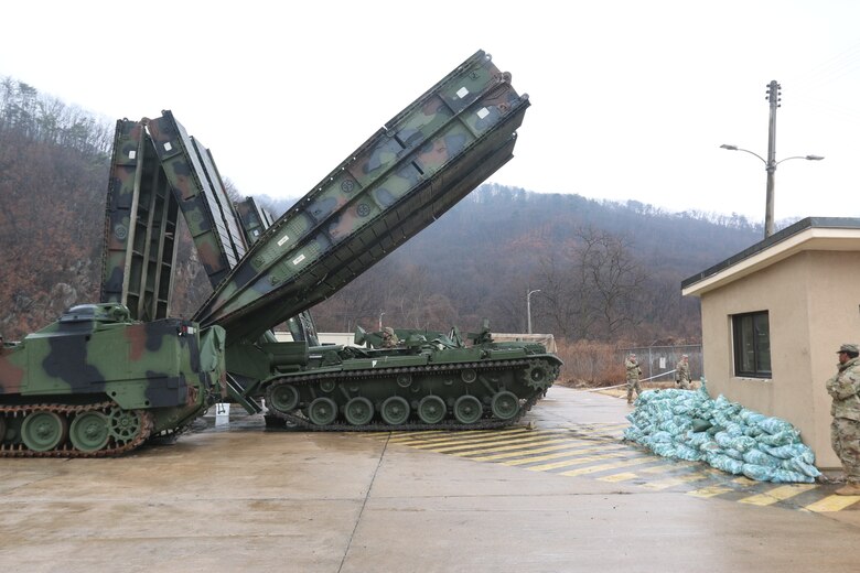 Soldiers use tanks to hoist portable bridges