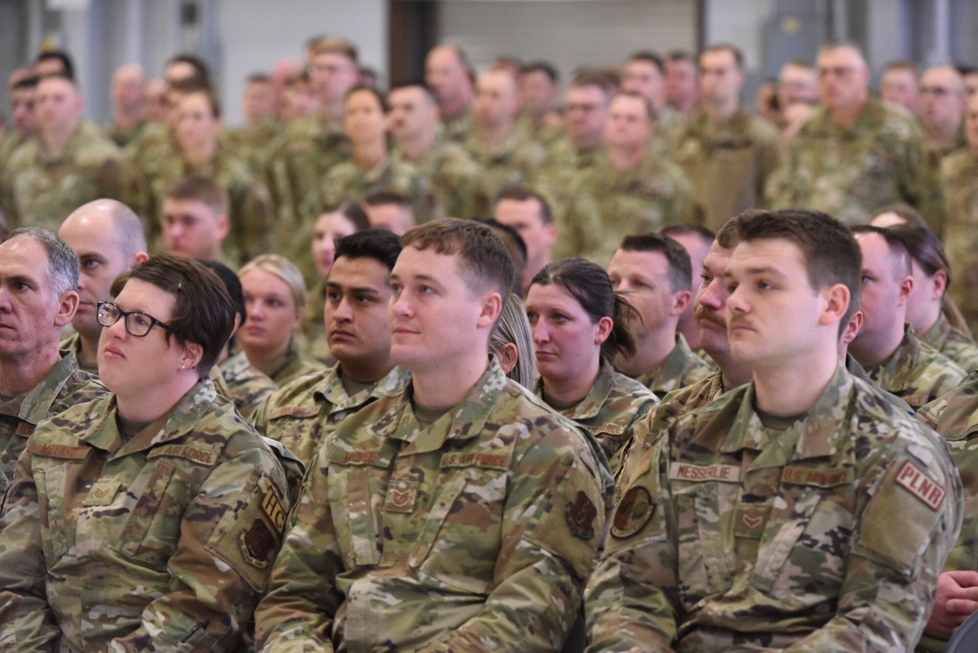 Airmen sit and stand in formation