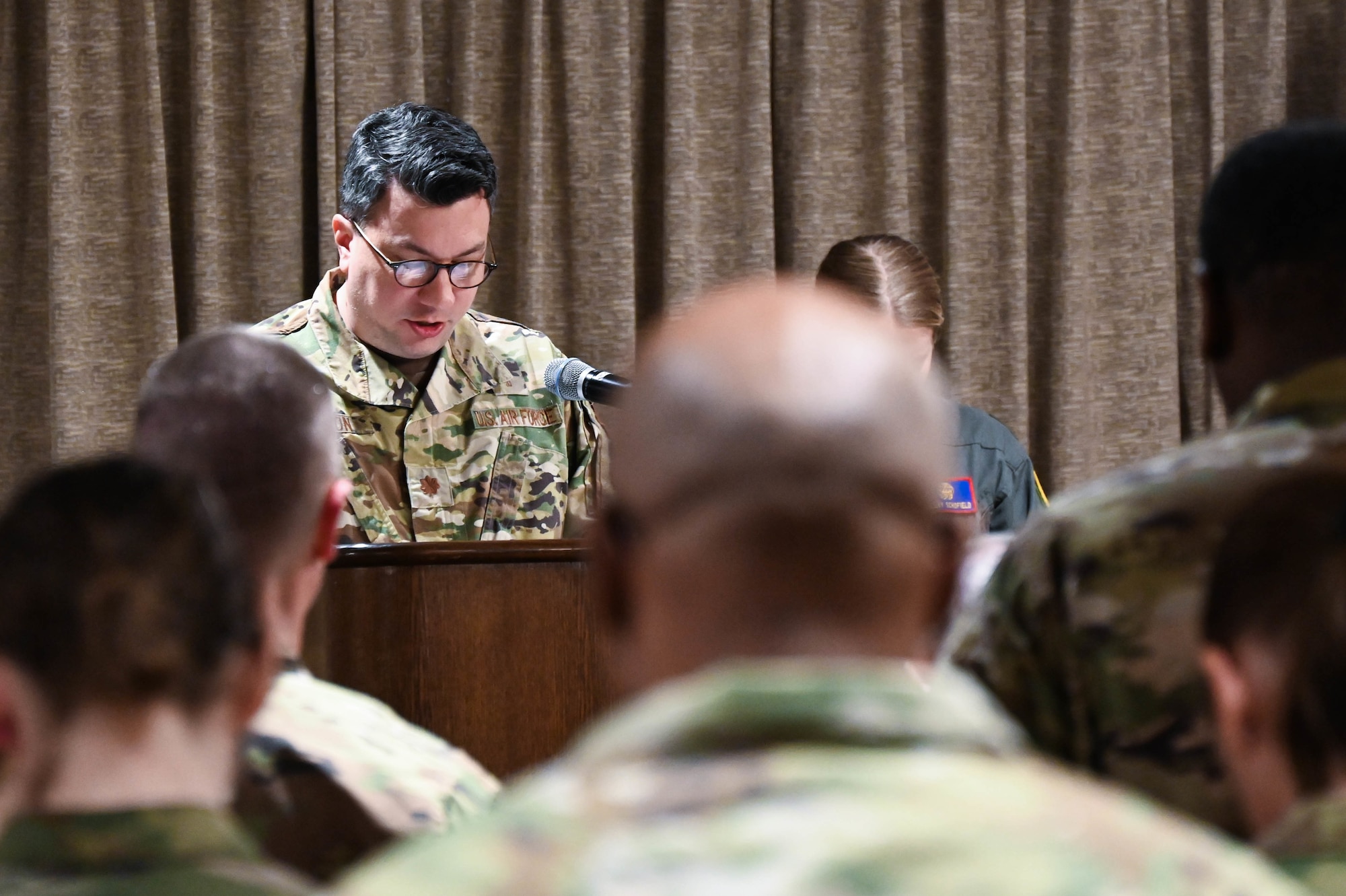 airman speaking at a podium in front of a crowd