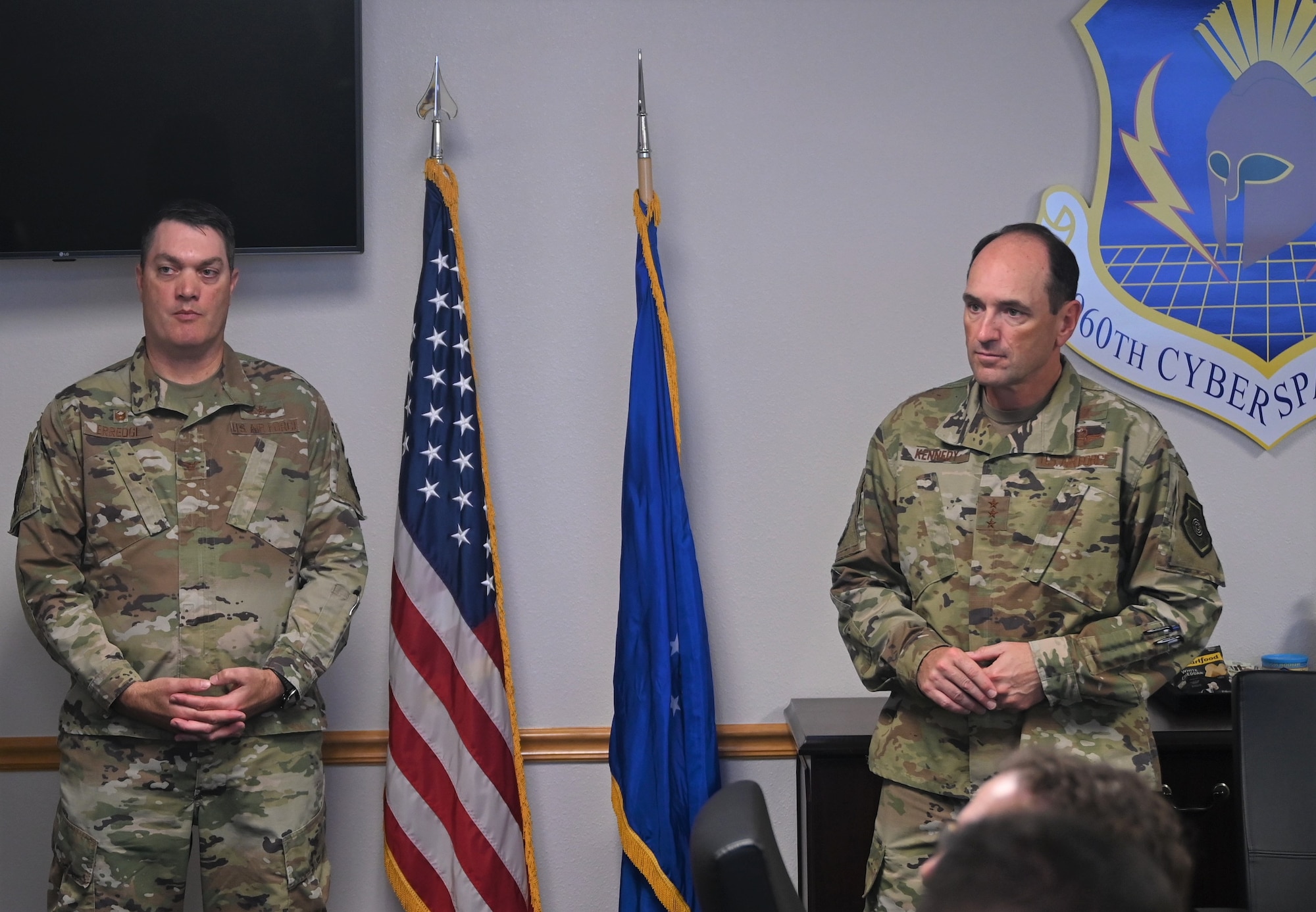 Lt. Gen. Kevin B. Kennedy is briefed by multiple personnel during his visit to the 960th Cyberspace Wing. Col. Richard Erredge provides further detail between speakers.