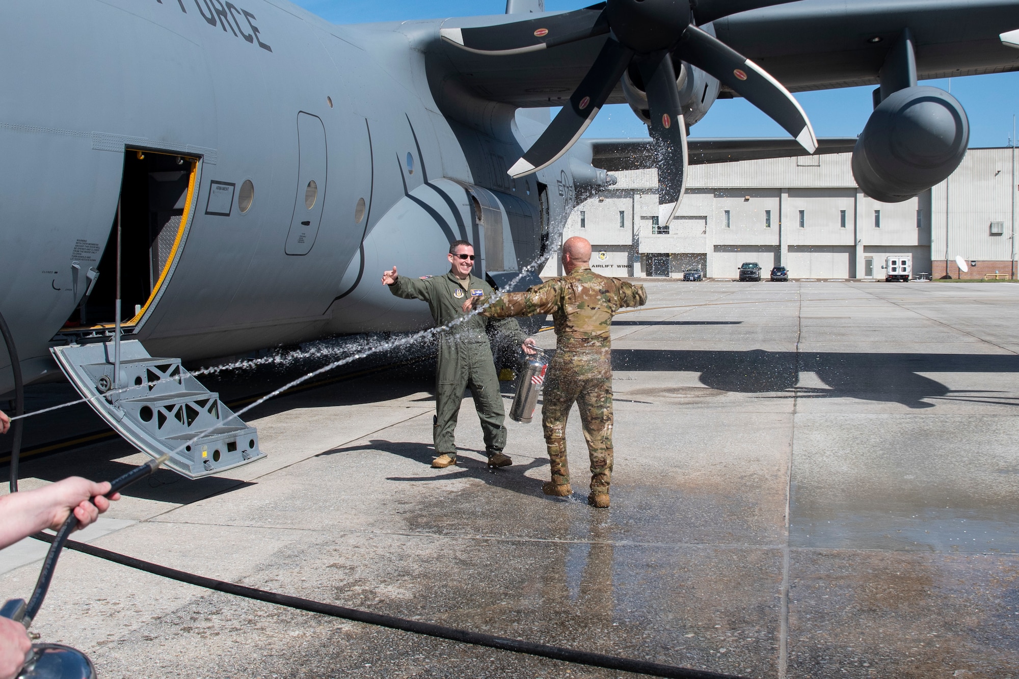 A man is sprayed with a hose after he gets off of an aircraft.